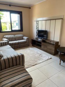 a living room with two couches and a flat screen tv at Casa de praia na Paraíso in Torres