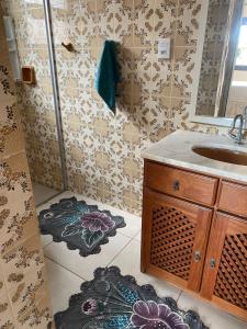 a bathroom with a sink and a mirror and a rug at Casa de praia na Paraíso in Torres