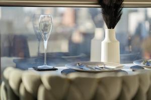 a table with a wine glass and plates and a vase at Emerald haven - Birmingham skyline view in Birmingham