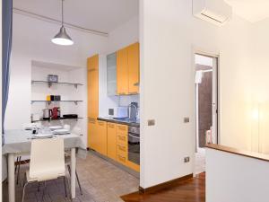 a kitchen with yellow cabinets and a table and chairs at Voltiva House - in the Heart of Como Old Town in Como