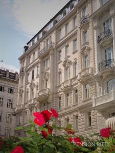 ein großes weißes Gebäude mit roten Blumen davor in der Unterkunft Pension Riedl in Wien