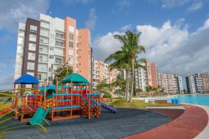 a playground in a park with a pool and buildings at Dreams Lagoon in Cancún