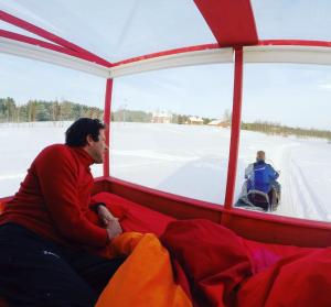 a man sitting in a tent looking out the window of a snowmobile at Lake Inari Mobile Cabins in Inari