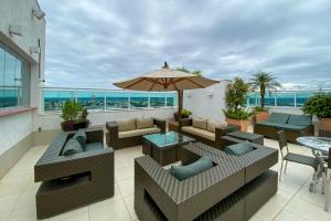 un patio con muebles y una sombrilla en el balcón en OZPED Flats Particulares Edifício Biarritz, en Brasilia