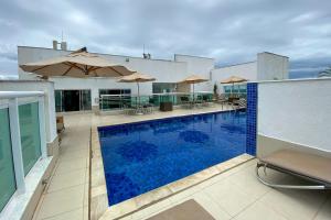 Una piscina con sillas y sombrillas en un edificio. en OZPED Flats Particulares Edifício Biarritz, en Brasilia