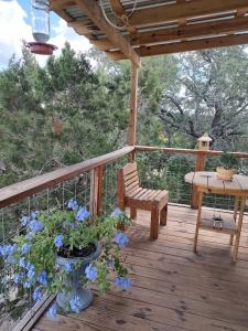 a wooden deck with a bench and a table and blue flowers at Boulderdash Birdhouse Studio in Bandera