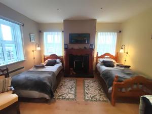 a living room with two beds and a fireplace at Ben Levy House Rental Suite, Clonbur Village in Clonbur