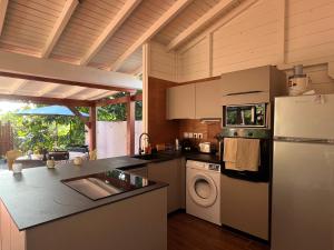 a kitchen with a refrigerator and a washing machine at Bungalow Corossol avec piscine in Le Gosier