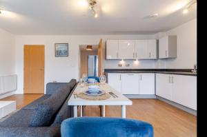 a kitchen and living room with a table and blue chairs at Modern 2 Bed Flat with Balcony, Easy London Access in London