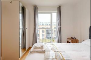 a bedroom with a bed and a large window at Modern 2 Bed Flat with Balcony, Easy London Access in London