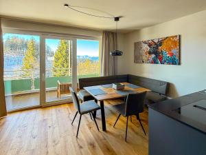 a living room with a table and chairs and a large window at Chalet1500 Apartment Gerlitzen - Kärnten Card inklusive! in Kanzelhöhe