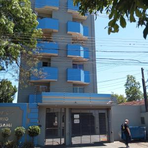 a man walks past a building with blue balconies at Próxima a UEM in Maringá