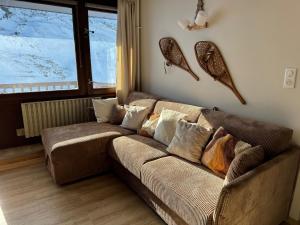 a brown couch in a living room with a window at Le Cocon in La Mongie