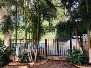 a fence with palm trees in front of a pool at La buena vida ocean Tamarindo in Tamarindo