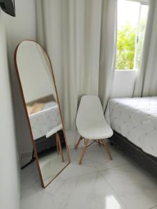 a mirror and a chair in a room with a bed at Casa aconchegante no centro da cidade in São Thomé das Letras +2 photos