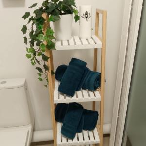 a wooden towel rack with blue towels and a toilet at COSYHOME - Studio Familial Confortable - Paris - CDG - Parking privé in Aulnay-sous-Bois