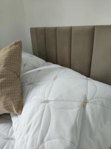 a bed with a white comforter and a pillow at Casa aconchegante no centro da cidade in São Thomé das Letras