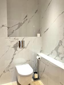 bagno con servizi igienici bianchi e pareti in marmo di Appartement Stella a Monticello Altre 3 foto