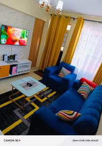 a living room with blue couches and a tv at ONE BEDROOM THIKA ROAD ,TRM DRIVE Homes by Essyruby in Nairobi