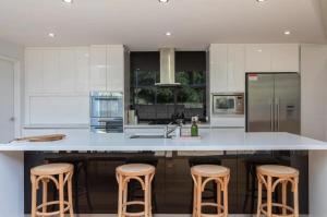 a kitchen with a large white island with stools at House on the Hillside with City Views Sleeps 12 in Howrah