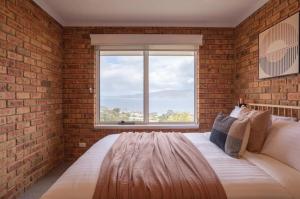 a brick walled bedroom with a large bed with a window at House on the Hillside with City Views Sleeps 12 in Howrah