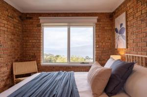 a brick walled bedroom with a bed and a window at House on the Hillside with City Views Sleeps 12 in Howrah