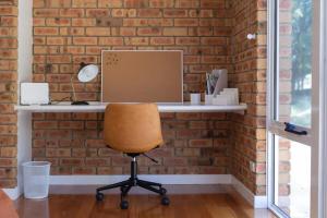 a desk with a computer on a brick wall at House on the Hillside with City Views Sleeps 12 in Howrah