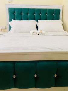a large bed with a blue headboard and white pillows at ONE BEDROOM THIKA ROAD ,TRM DRIVE Homes by Essyruby in Nairobi
