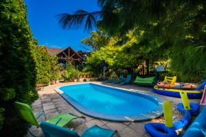 a swimming pool with chairs and a playground at Katica Vendégház in Siófok
