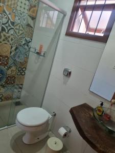 a bathroom with a toilet and a glass shower at Hospedagem Sil e Jean quarto triplo, cozinha compartilhada com outros hóspedes in São Gabriel