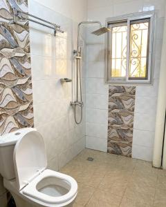 a bathroom with a toilet and a shower with a window at Luma in Yaoundé