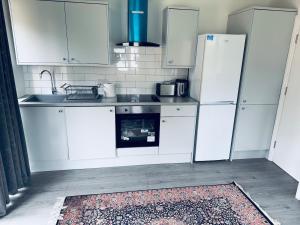 a kitchen with white cabinets and a sink and refrigerator at A cozy apartment in Windsor +4 photos