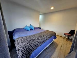 a bedroom with a bed with blue pillows and a chair at Elysium de Uco in Tupungato +28 photos
