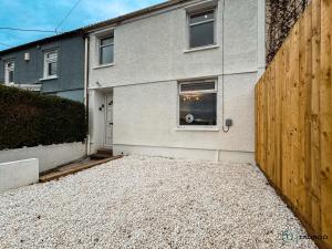 a house with a wooden fence next to a driveway at Silver Birch - Dowlais in Merthyr Tydfil
