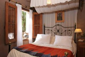 a bedroom with a bed with white pillows and a window at Quinta La Paceña in Tilcara