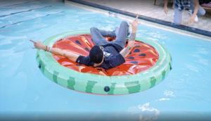 a person laying on an inflatablelatable circle in a swimming pool at Sky-Rise Apartments in Los Angeles