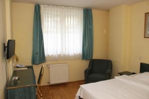 a room with a bed, chair, desk and window at Hotel Bara Budapest in Budapest