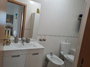 a white bathroom with a sink and a toilet at Linas Guesthouse in Parchal
