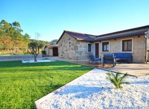 a stone house with a patio and a yard at GALIHOST - A casa de Alsira in Ribadumia