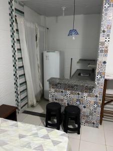 a kitchen with two stools and a counter with a refrigerator at Pousada encasa in São Mateus