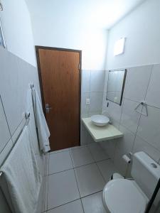 a white bathroom with a toilet and a sink at Pousada Costa Prestige in Touros