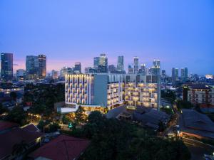 a lit up building with a city skyline in the background at Ayaka Suites in Jakarta