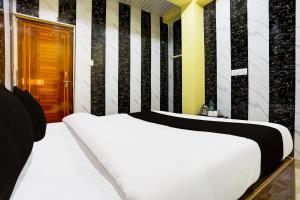 Una cama blanca en una habitación con rayas blancas y negras. en HOTEL O ELEGANT, en Prayagraj 30 fotos más