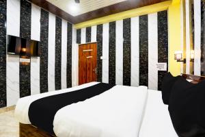 1 dormitorio con cama blanca y pared de rayas en blanco y negro en HOTEL O ELEGANT, en Prayagraj