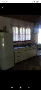 a kitchen with white cabinets and a white refrigerator at Cabaña con piscina compartida in Mina Clavero