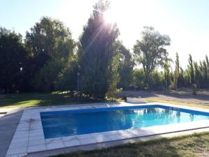 a swimming pool in a yard with the sun shining at Cabañas EL BOSQUE in Malargüe