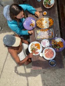 two people sitting at a wooden table eating food at Puemape Planet Eco Hostel in Puémape