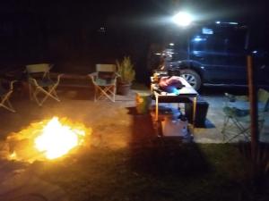 a man is sitting at a table next to a fire at Mantiqueira lar doce lar in Gonçalves