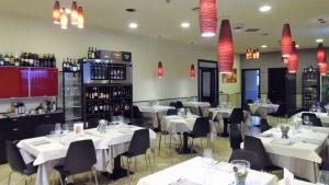 ein Restaurant mit weißen Tischen, Stühlen und Weinflaschen in der Unterkunft Albergo Sirena in Bazzano Bologna