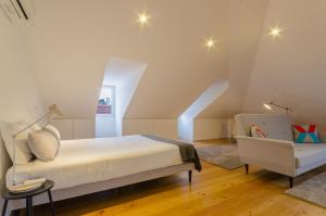 a white bedroom with a bed and a chair at Casas da Baixa - Lighthouse Apartments in Lisbon